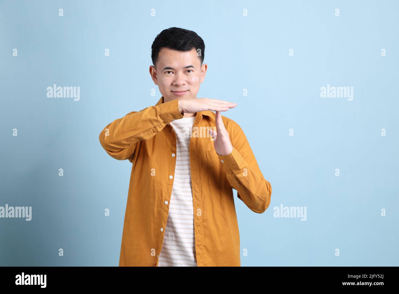 The Asian LGBTQ man with yellow shirt standing on the blue background. Stock Photo