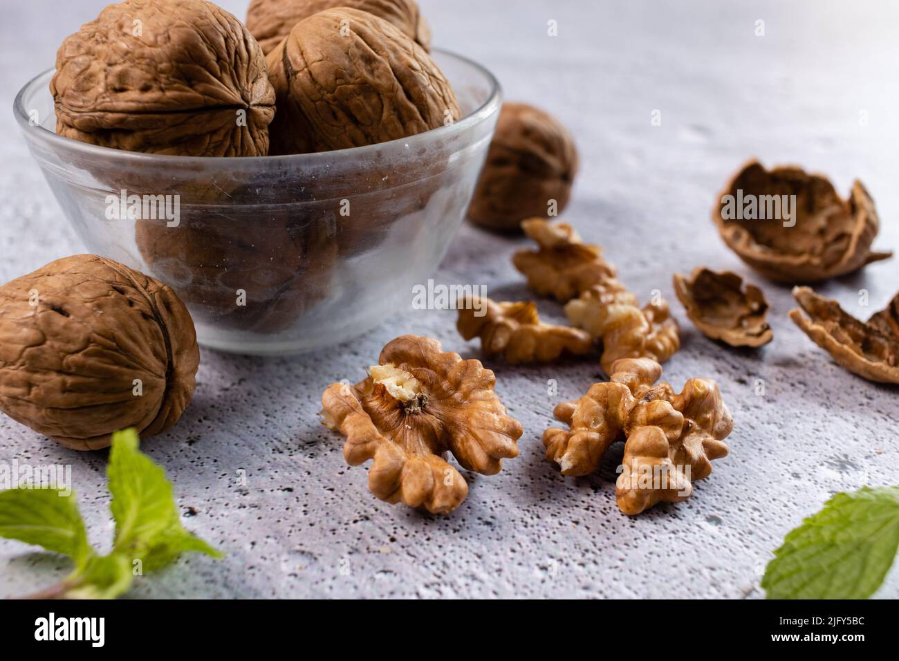 Selective focus on walnuts in a bowl and kernels on white background Stock Photo