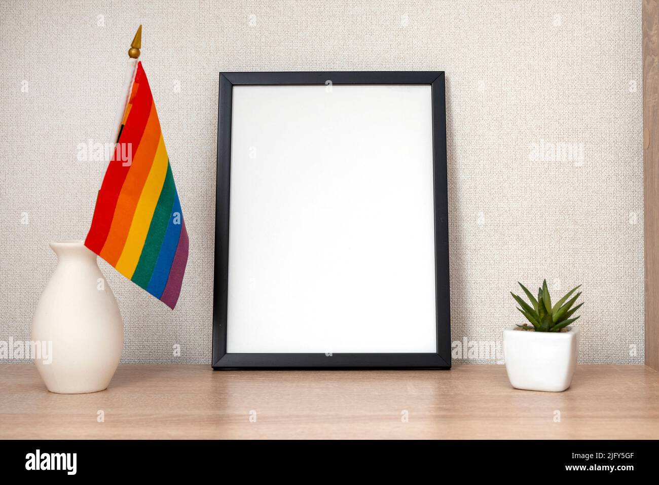 LGBT office, desk with rainbow flag and stationery, blank frame with space for text Stock Photo