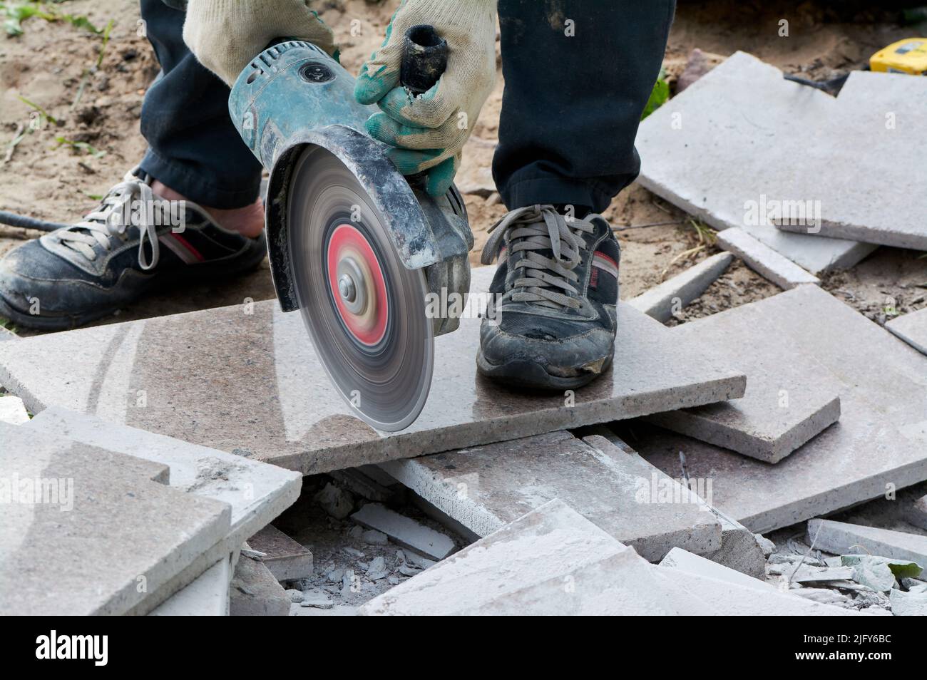 A worker with a circular saw cuts a tile in close-up. Stock Photo