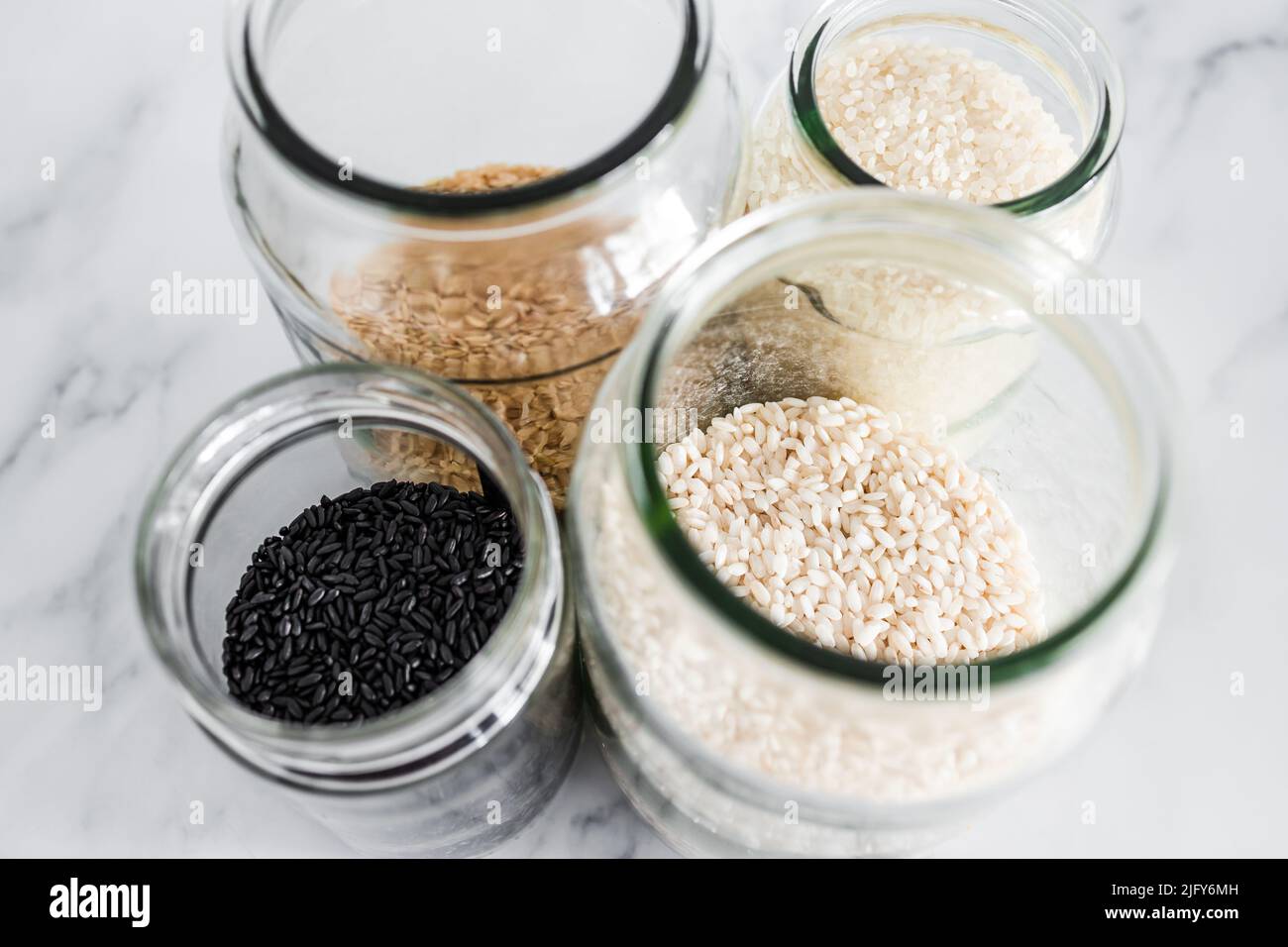 pantry jars with different types of rice including black brown arborio
