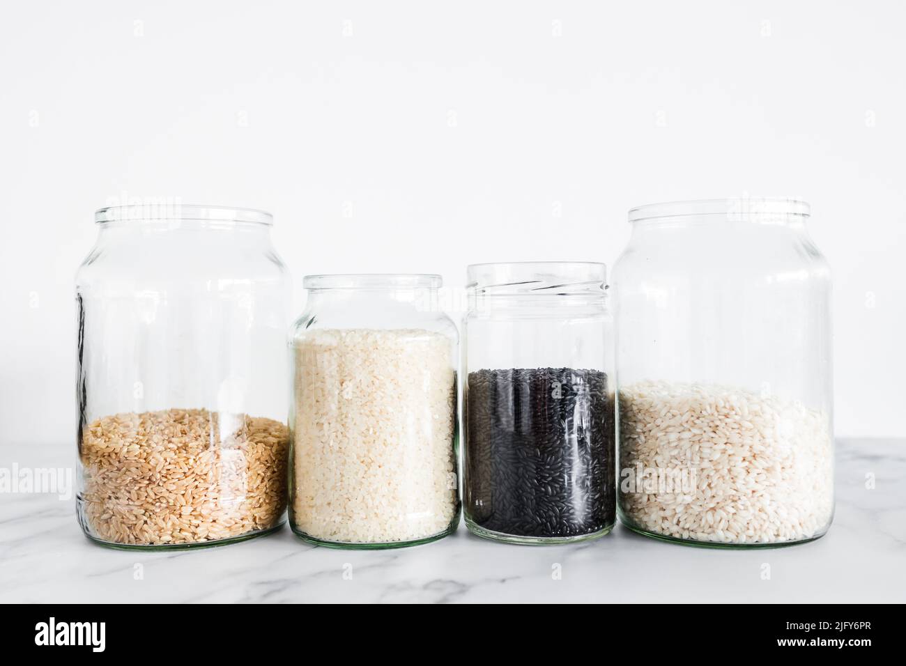 pantry jars with different types of rice including black brown arborio