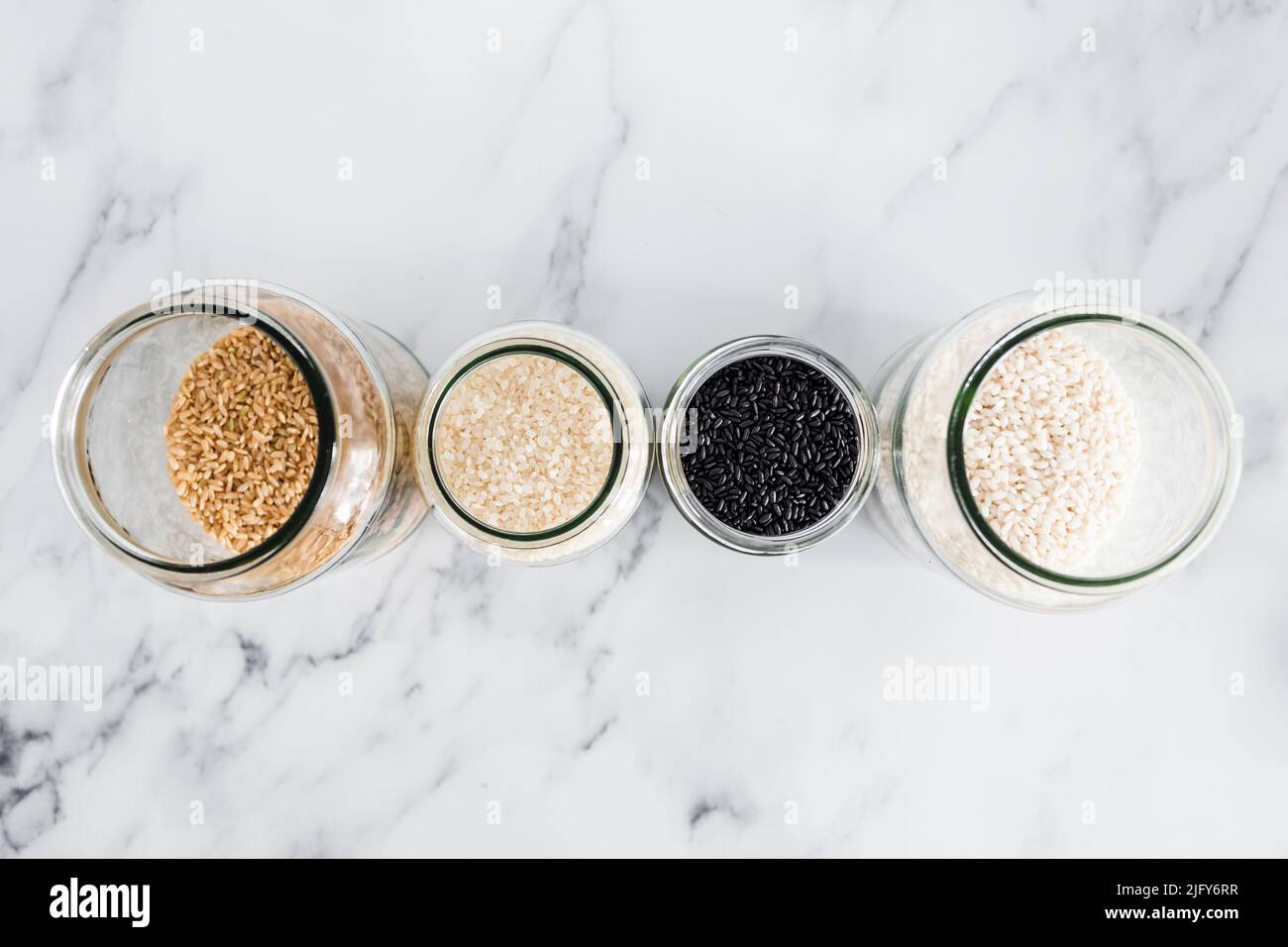 pantry jars with different types of rice including black brown arborio