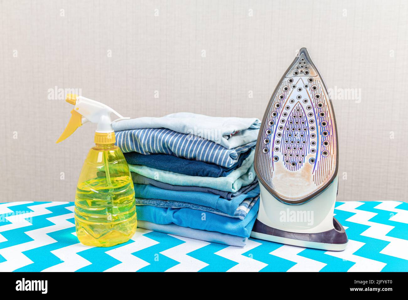 Electric iron on ironing board and water spray for ironing Stock Photo