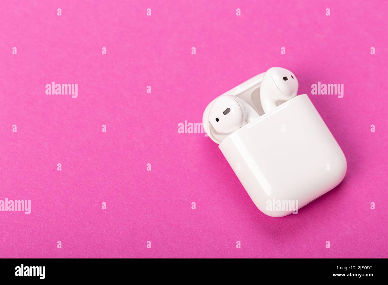 Modern wireless bluetooth headphones with charging case on purplepink