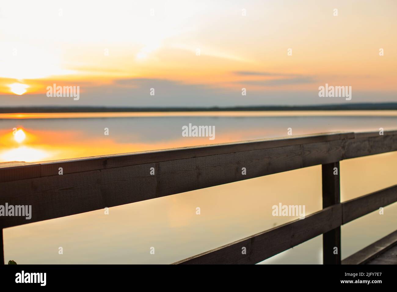 sunset on a wooden pier. Autumn landscape with falling leaves. Stock Photo