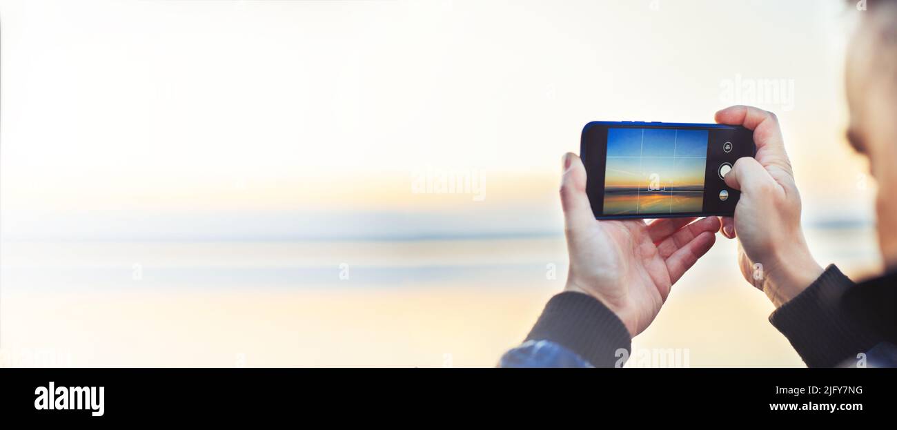 A man taking a photo of the beautiful sunset on his phone. travel concept Stock Photo