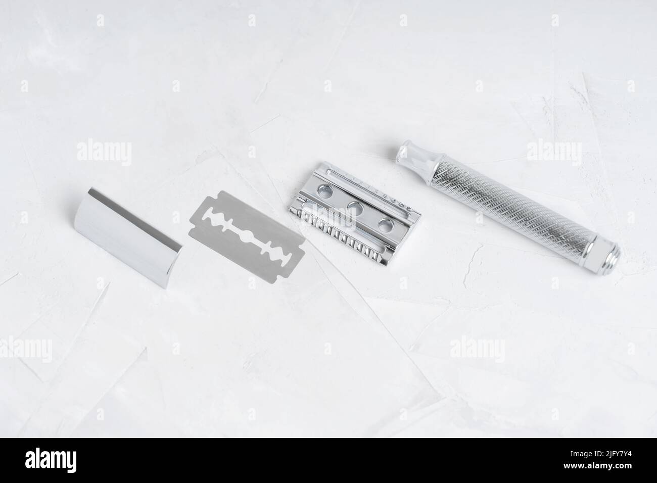 Safety razor parts and a blade arranged on a concrete background Stock