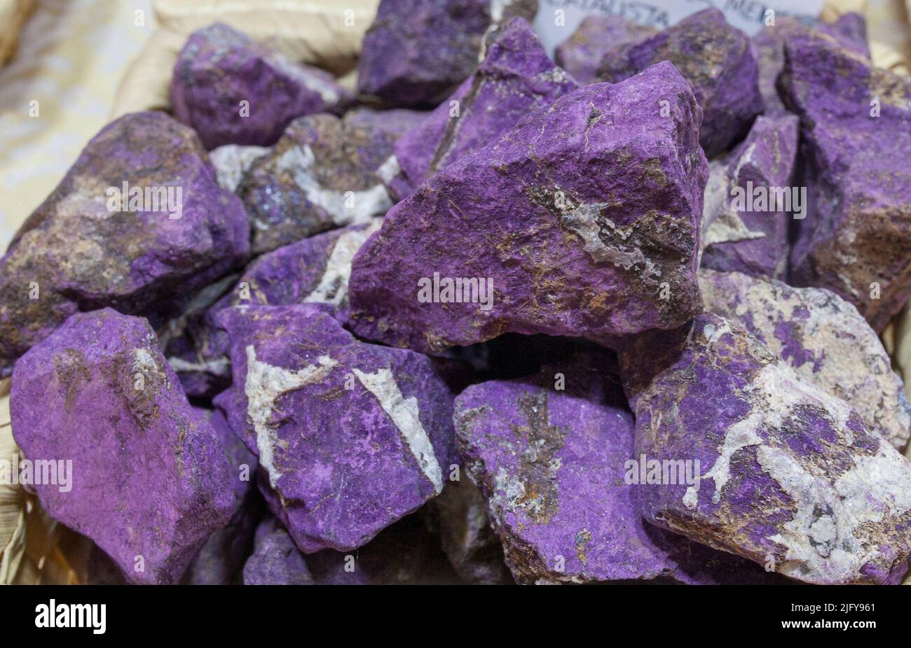 Fragments of purpurite believed to have beneficial health properties. Displayed on basket at street market stall Stock Photo