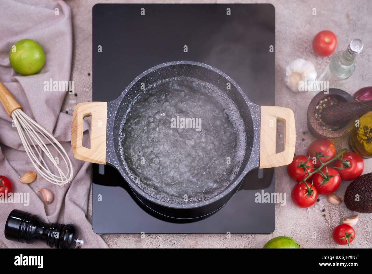 Boiling water in a cooking pot an a pan on a induction stove at