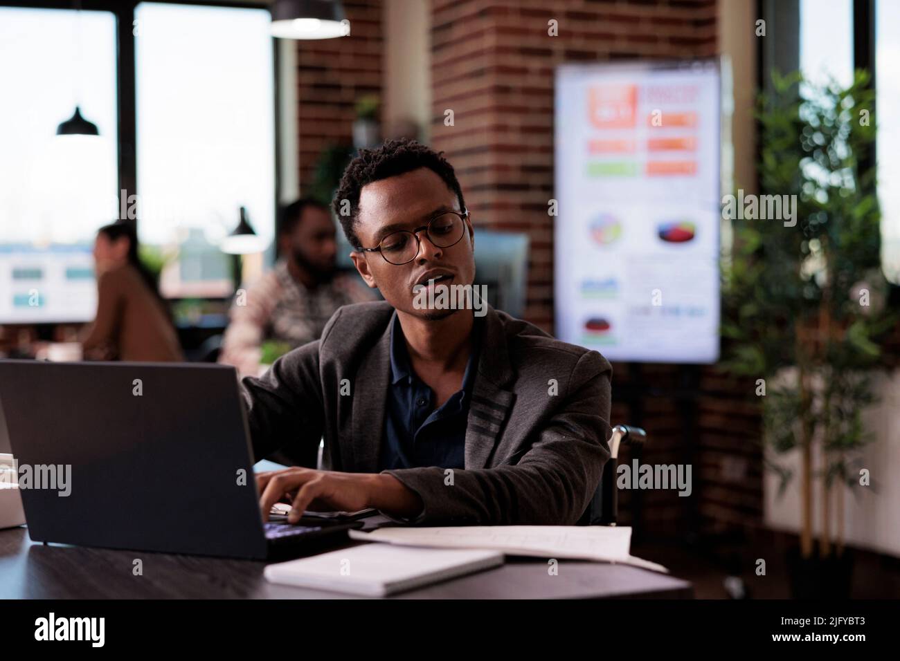 Young wheelchair user with physical health condition working on laptop