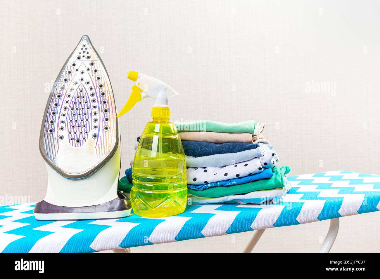 Electric iron on ironing board and water spray for ironing Stock Photo