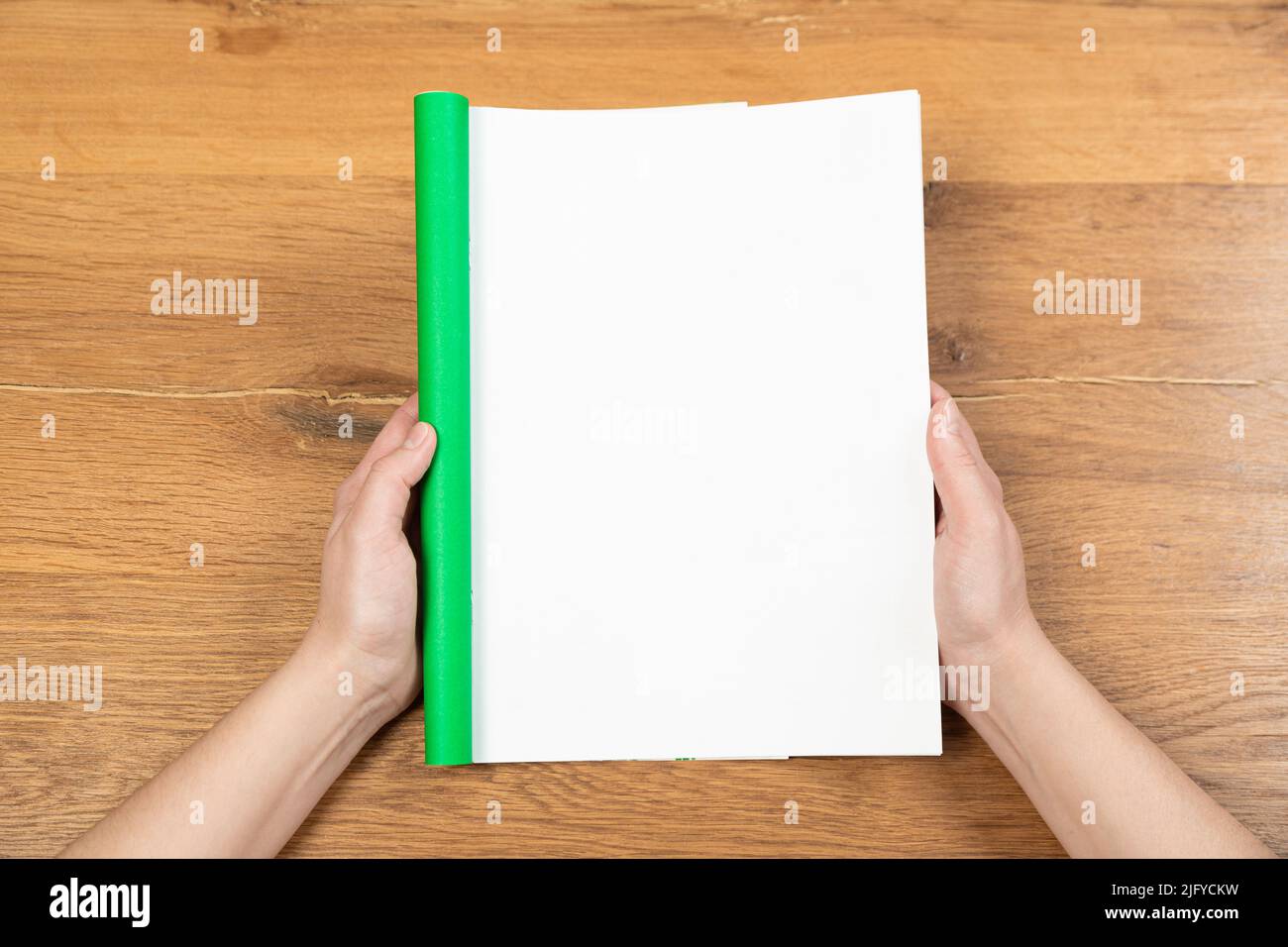 Woman's hands open empty catalog, magazines, book mockup on wooden
