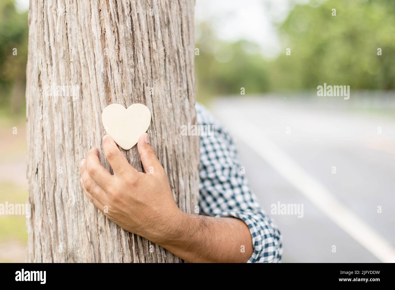 Tree hugging. Asian man giving a heart and a hug on big tree. Love tree and nature or environment concept Stock Photo