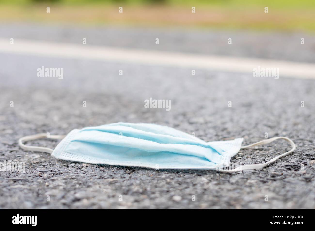 Old blue protective mask is on the road. After used and garbage concept