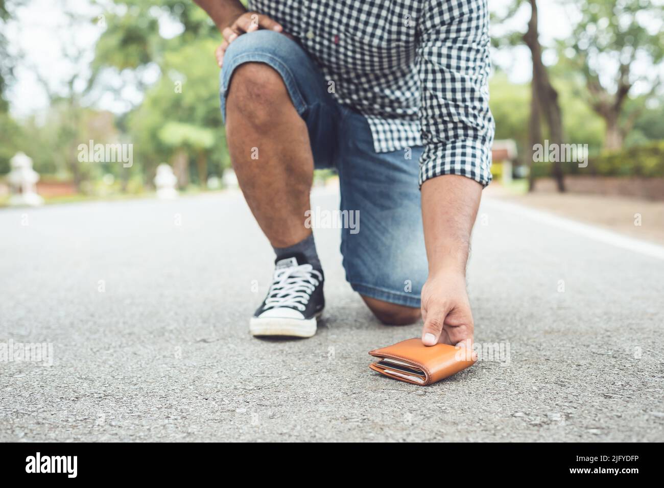 Asian man lose brown wallet on the road in tourist attraction. Losing wallet concept. Focus on wallet Stock Photo