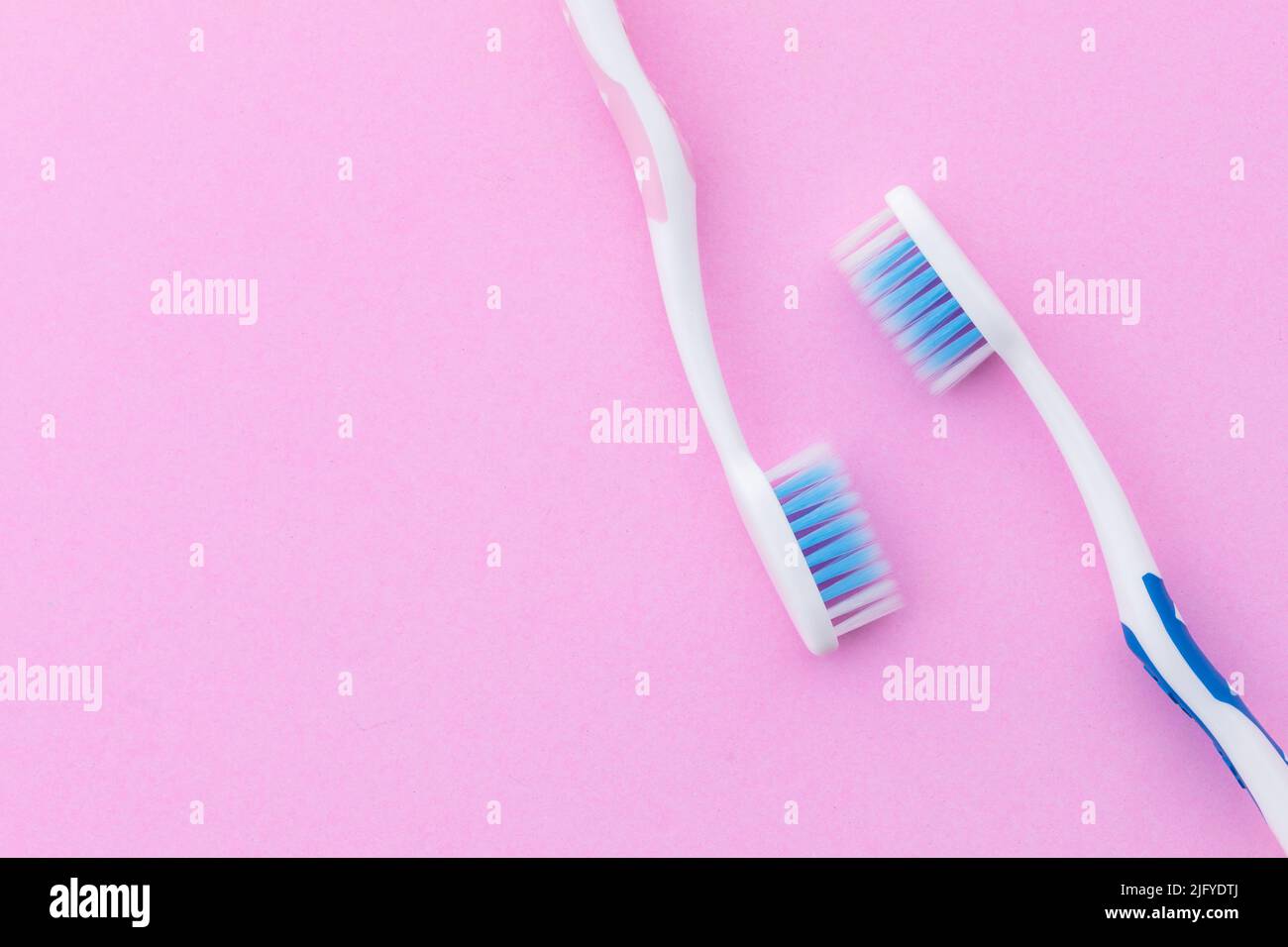 Top view new pink and blue toothbrush on pink background with copy space for text or design. Stock Photo