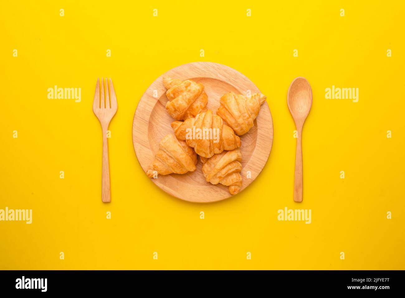Top view mini Croissant in wooden dish on yellow background. Food concept with copy space Stock Photo