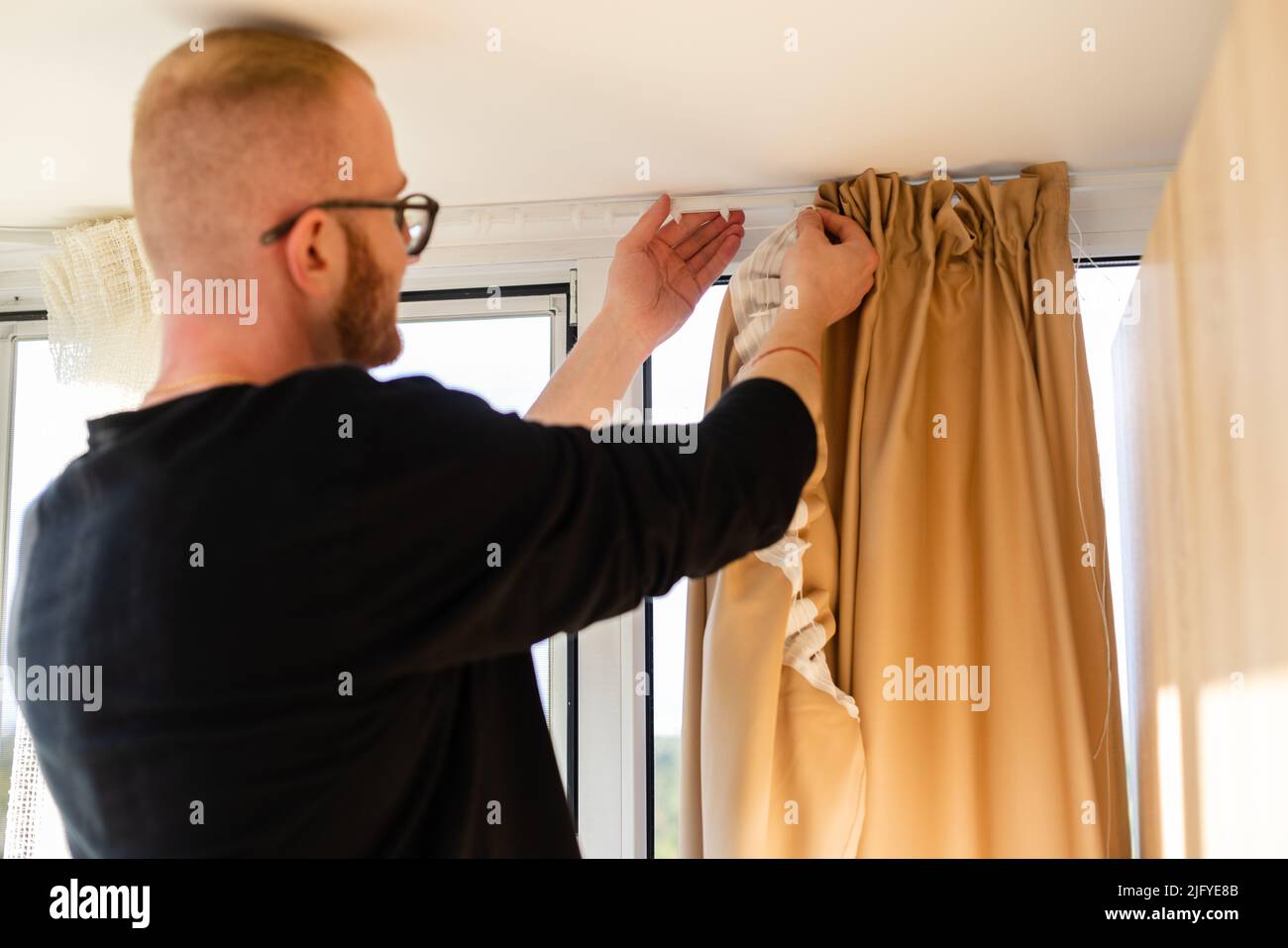 Man hanging curtains on the plastic hooks Stock Photo - Alamy