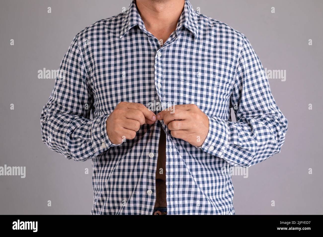 Close up man buttoning shirt studio shot on grey background Stock Photo