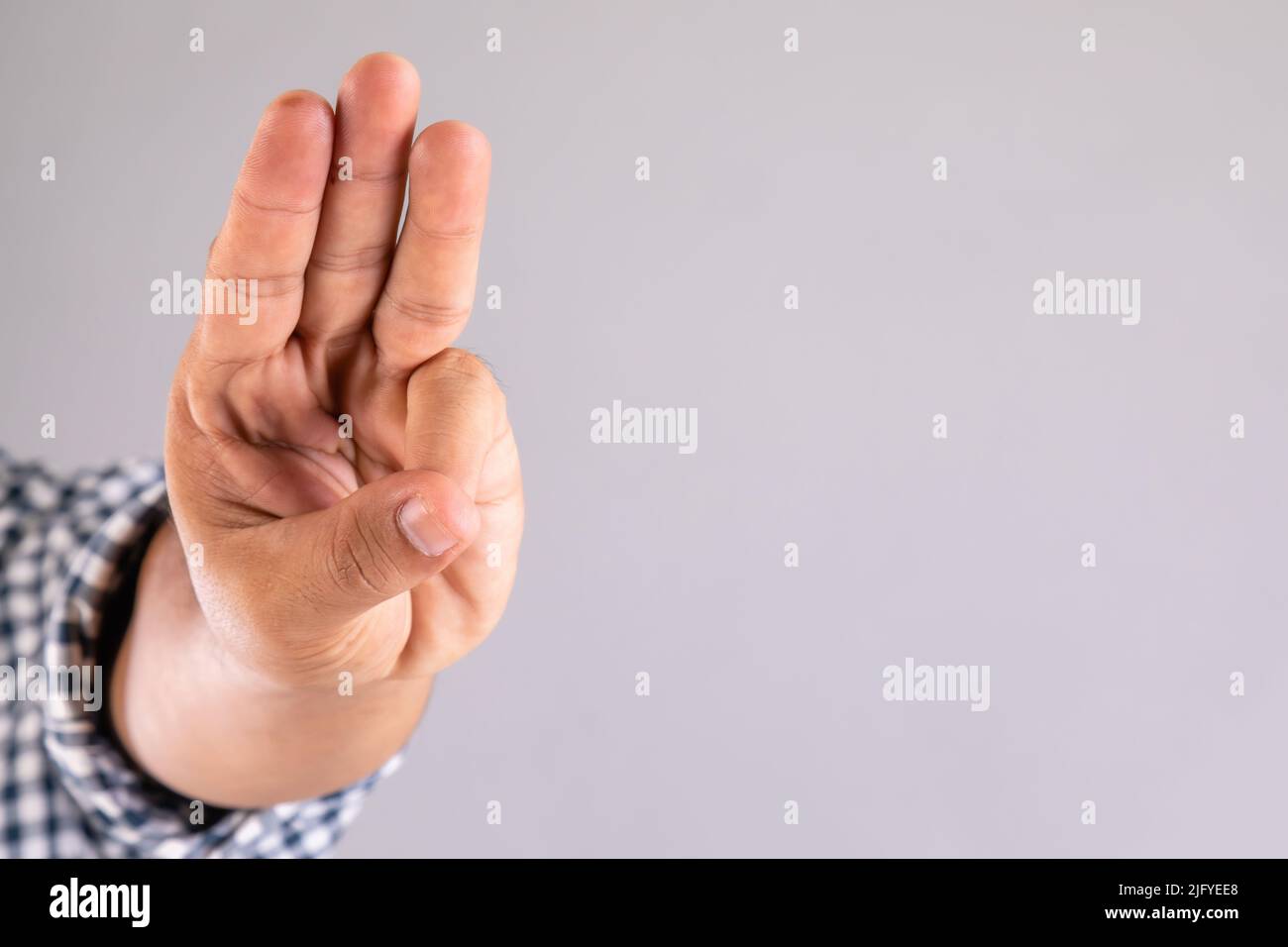 Close up hand showing three finger symbol on grey background with copy space Stock Photo