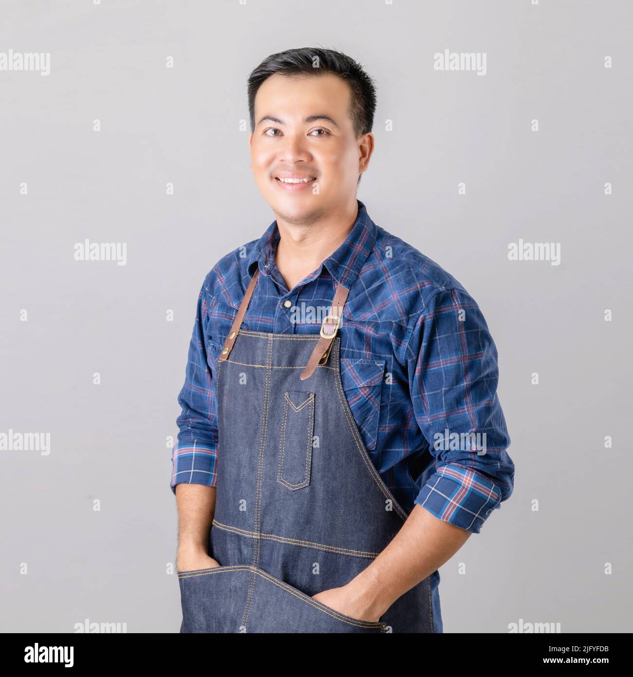 Portrait Asian man in barista uniform standing in studio isolated on grey background Stock Photo