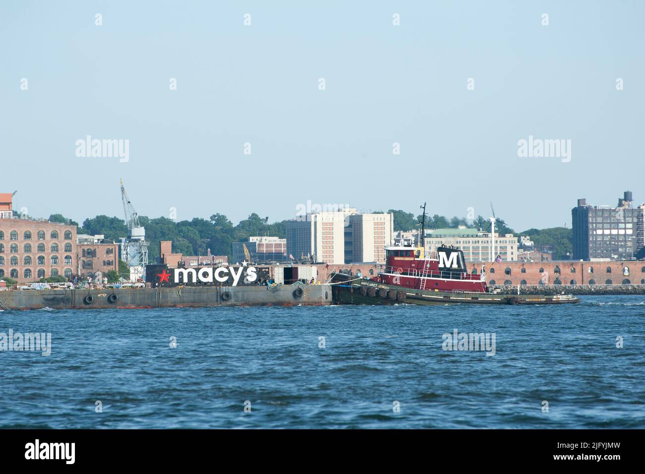 A Moran tugboat pushed a barge laden with fireworks up the East River for use in the annual Macy's July 4 fireworks display. July 4, 2022 Stock Photo