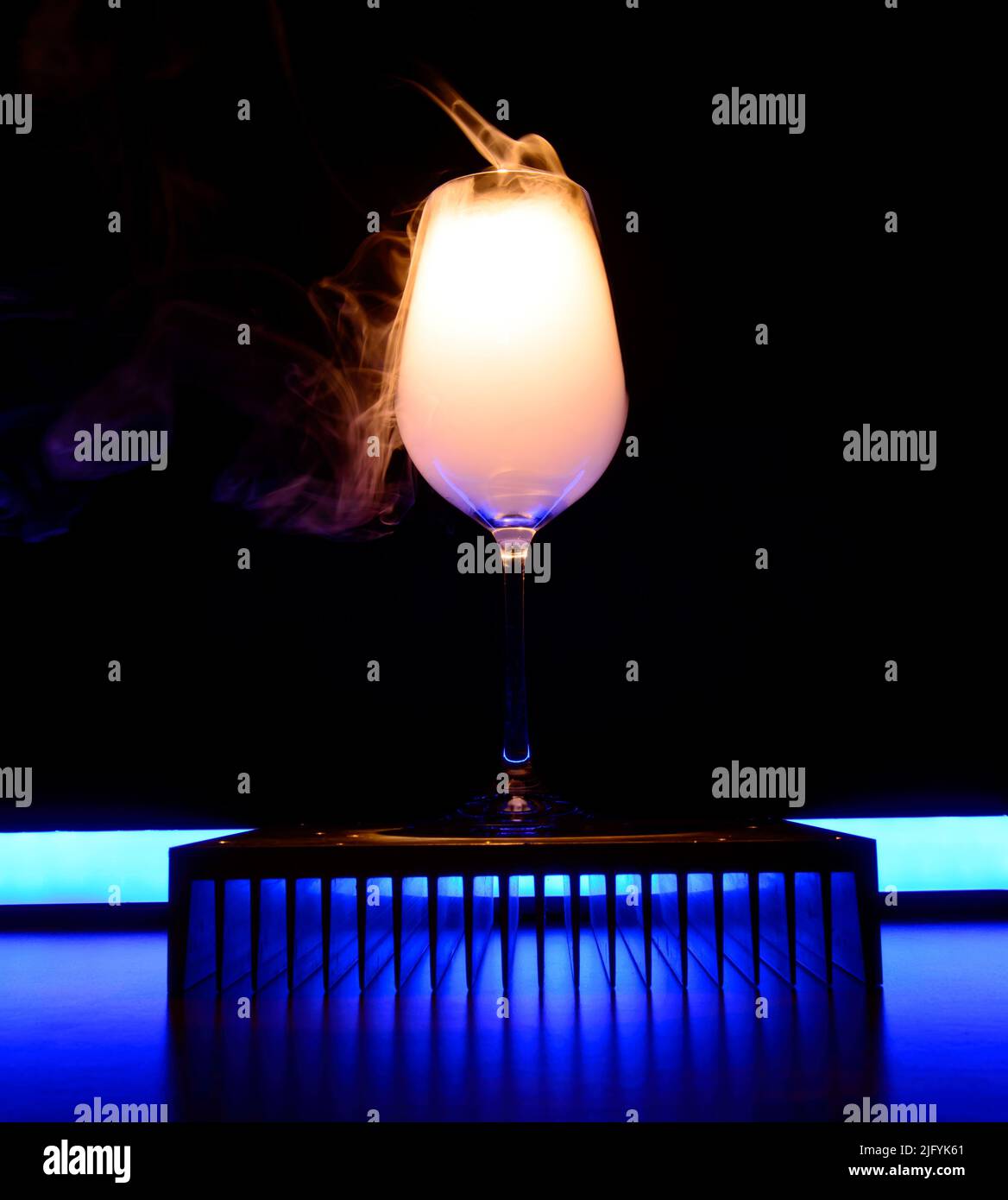 Wine glass filled with an alcohol vapors is standing on an aluminium stand with the backlight. Strong chemical reaction. Background picture. Stock Photo