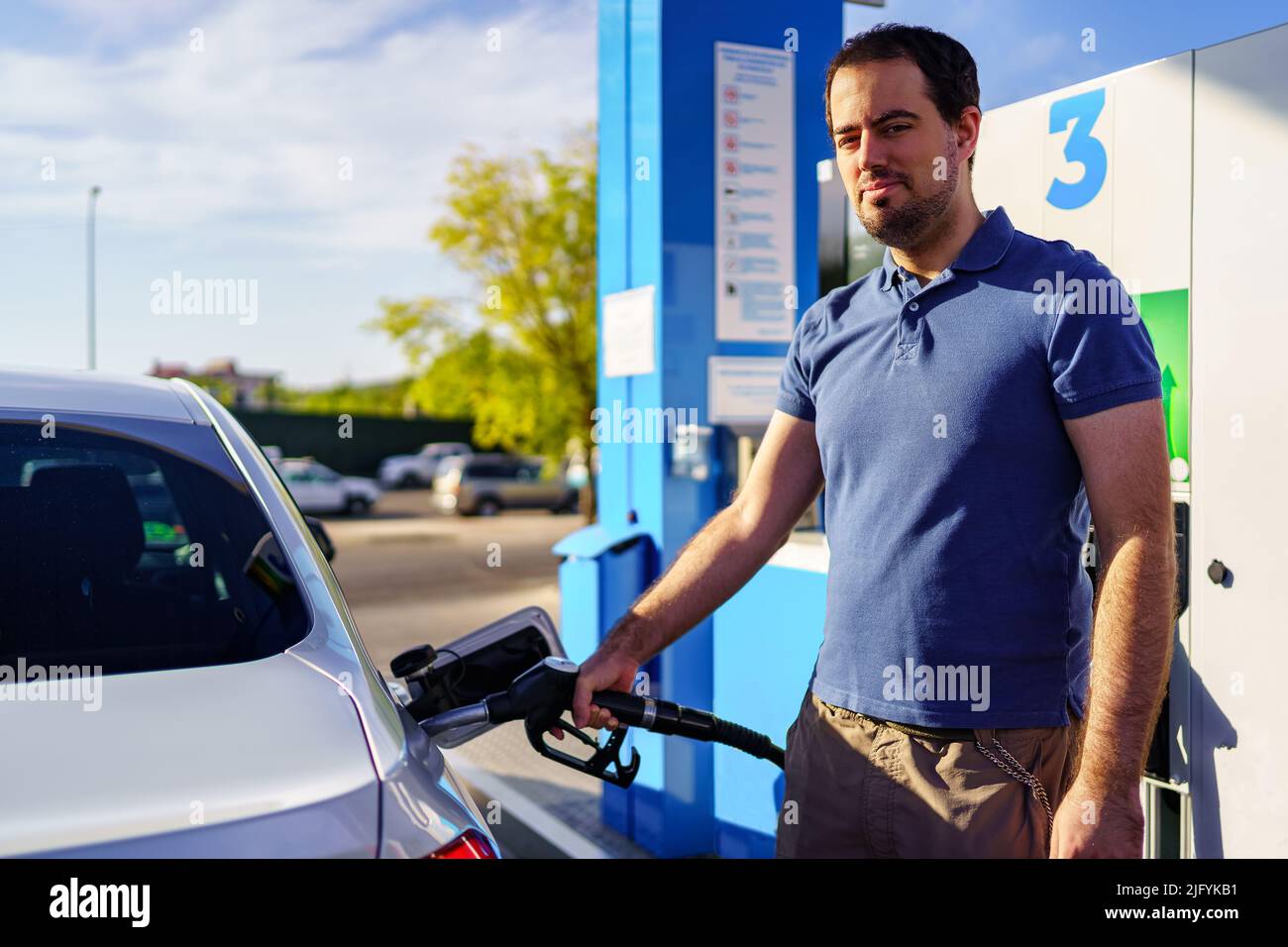 Adult man filling the gas tank of a car at the gas station Stock Photo