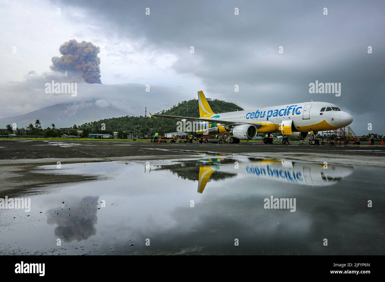 Erupting Mayon volcano, Cebu Pacific plane reflection in Legazpi airport, Bicol, Philippines natural disaster, Philippine volcanic explosive eruption Stock Photo