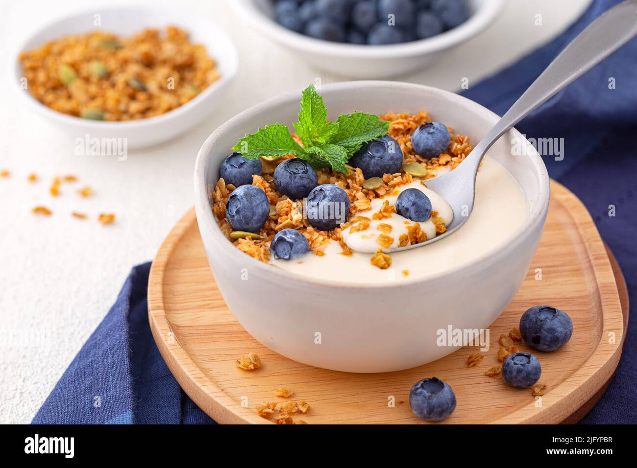Dairy free almond milk yogurt topped with granola and blueberries with copy space Stock Photo