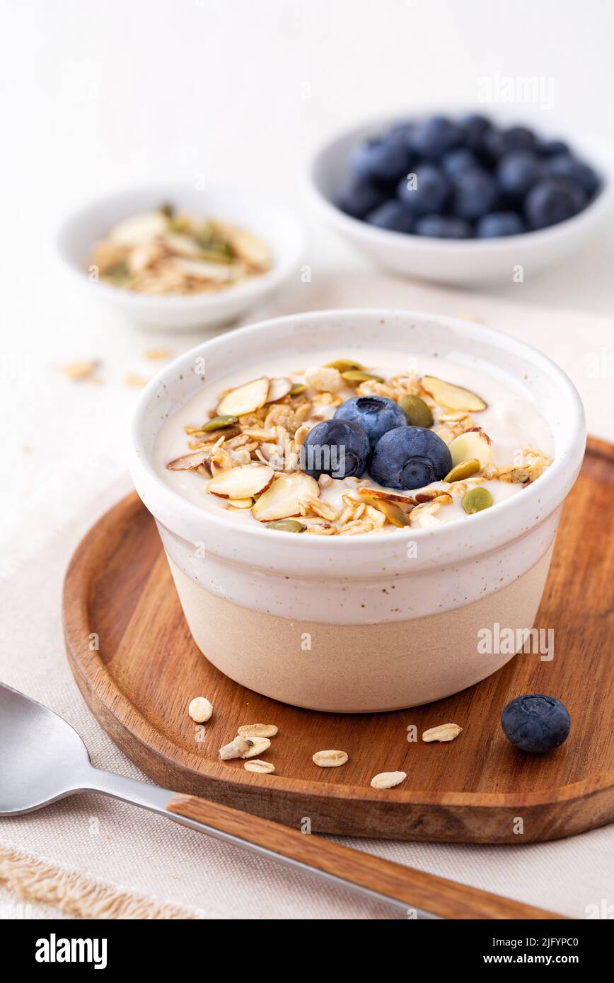 Dairy free almond milk yogurt topped with granola and blueberries with copy space Stock Photo