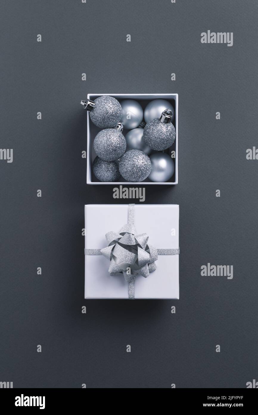 Open festive gift box with grey Christmas decorations on gray background. Flat lay, copy space. Stock Photo