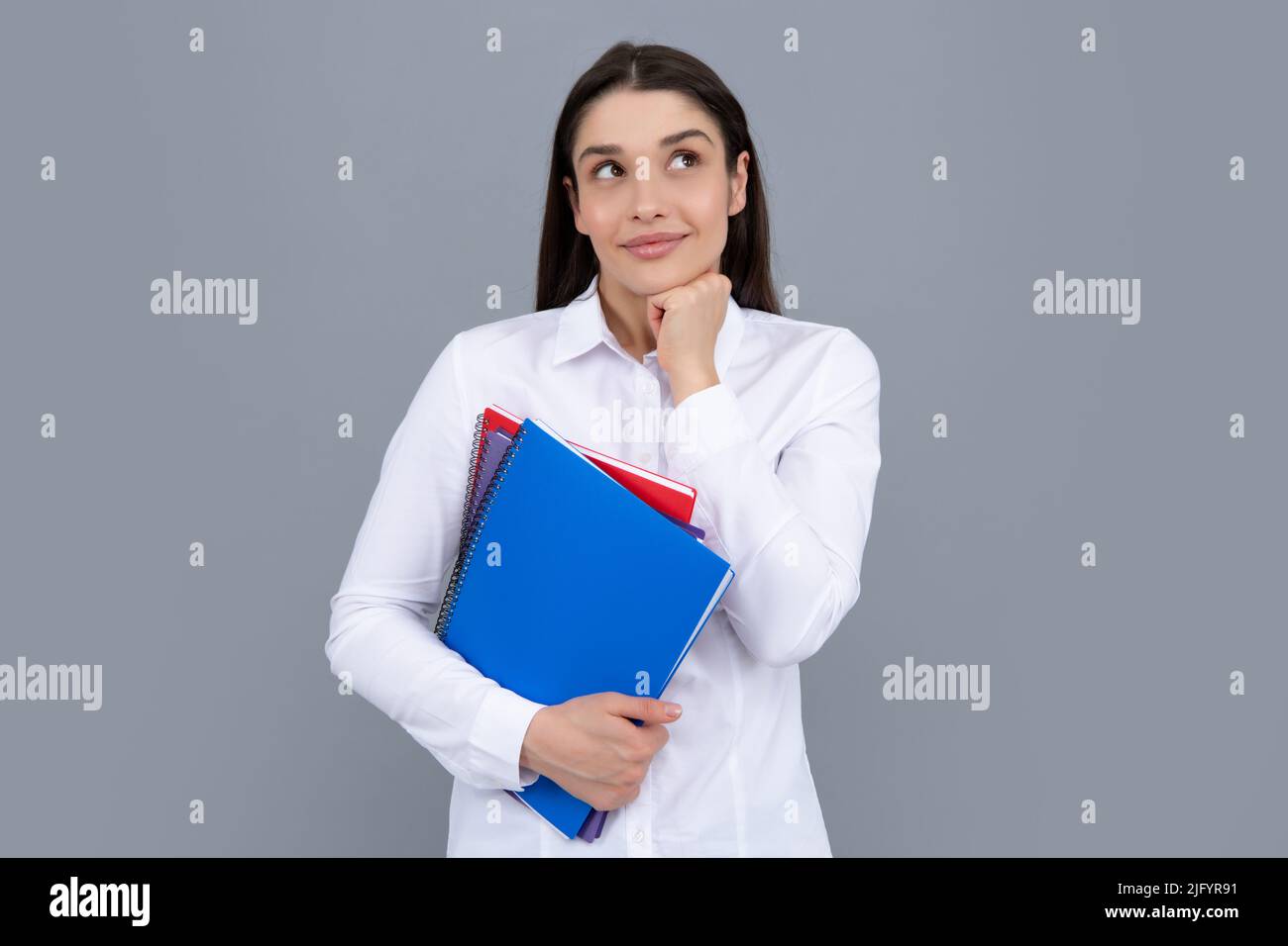 Female student holds books isolated on gray background in studio ...