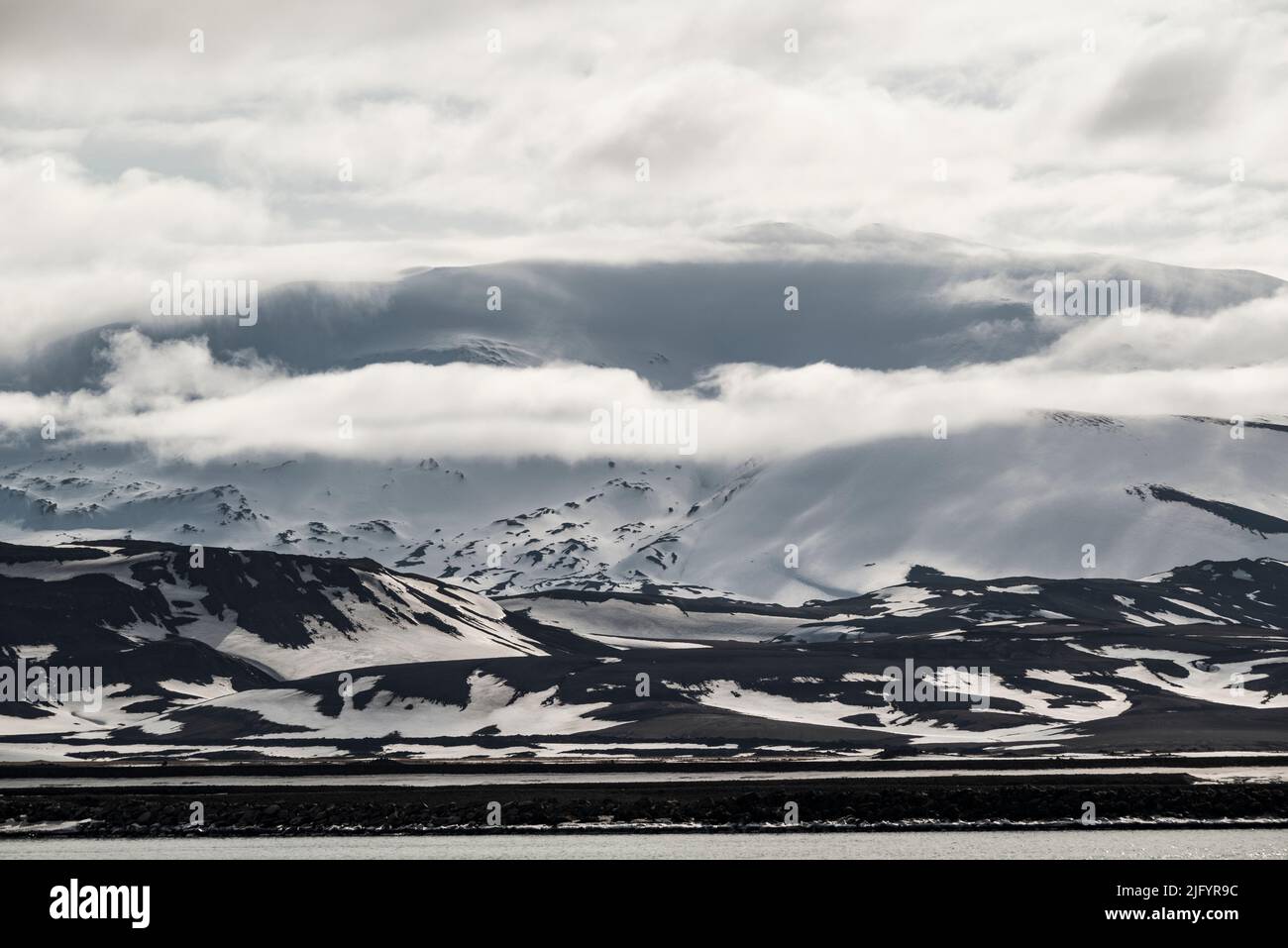 Sunlit clouds covering the summit of Hekla volcano in the winter landscape in upper Þjórsárdalur valley, Iceland Stock Photo