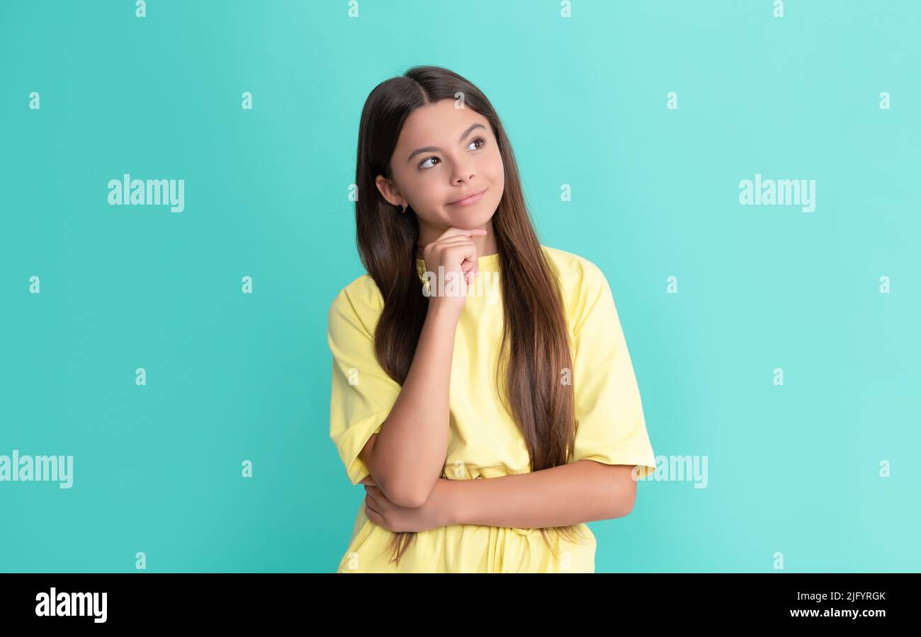 pondering teen girl with long hair on blue background, making decision Stock Photo