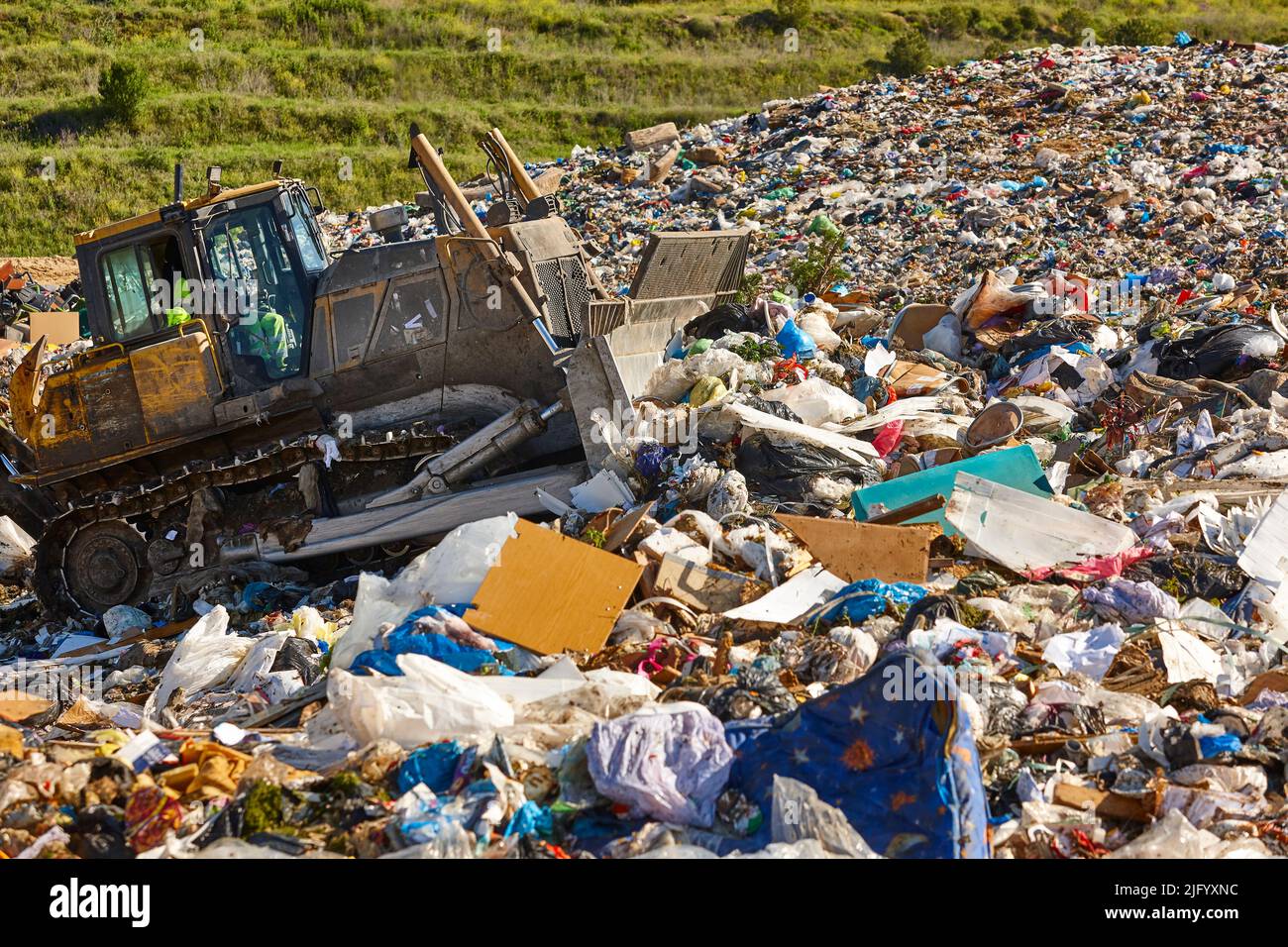 Heavy machinery shredding garbage in an open air landfill. Waste Stock