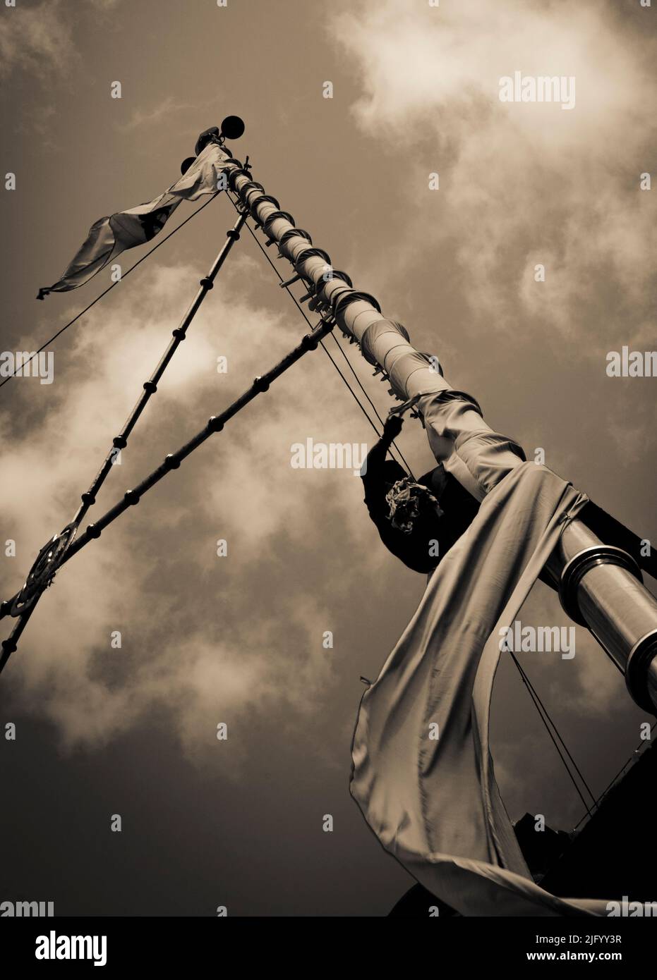 A low angle shot of a post with Nishan Sahib flag on it against a cloudy sky shot in monochrome Stock Photo