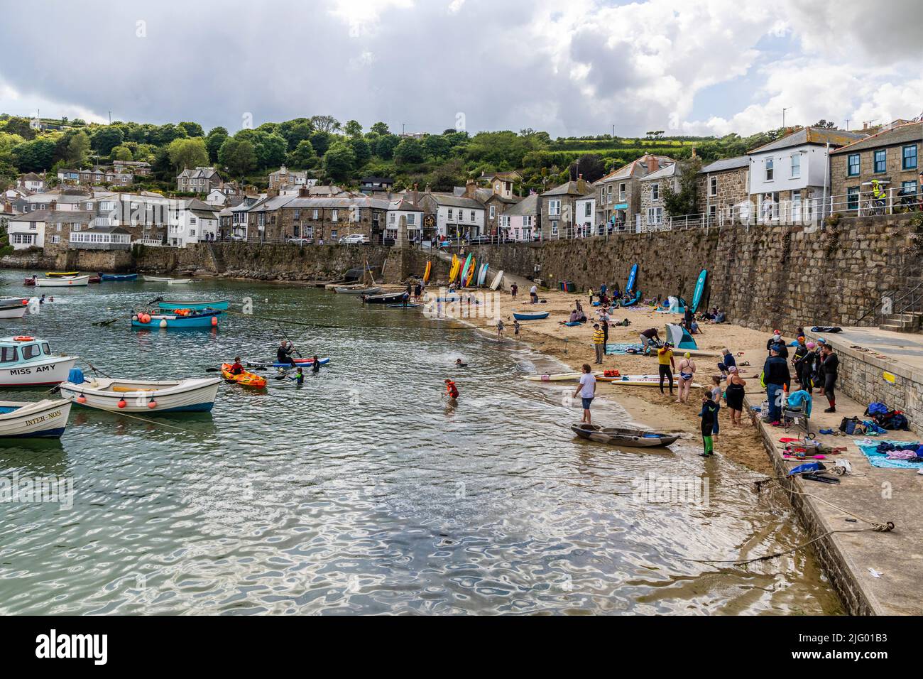 Club of wild swimmers preparing to swim from Mousehole harbour, Cornwall Stock Photo