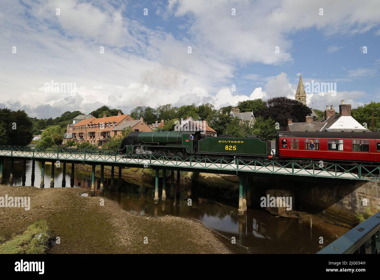 Steam Train (SR S15 class locomotive) pulling red passenger carriages across river Esk, North Yorkshire, UK Stock Photo