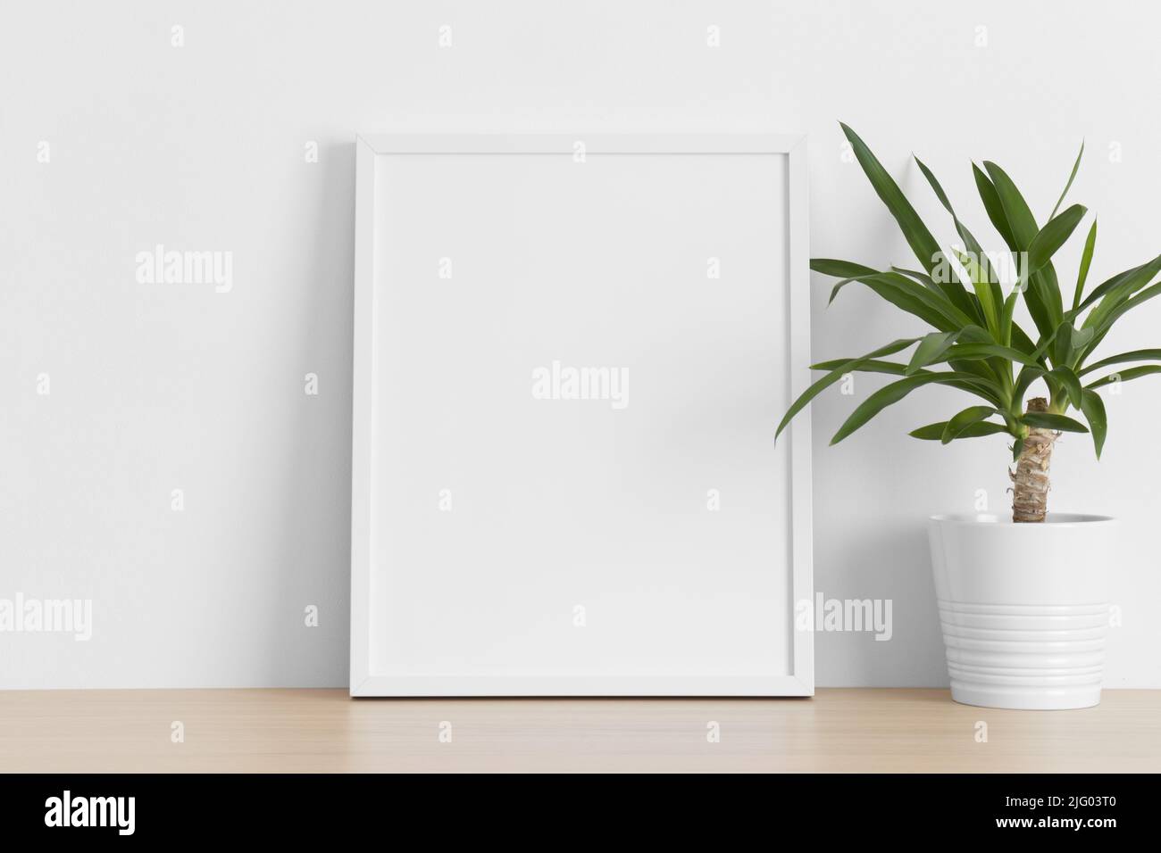 White frame mockup with a yucca plant on the wooden table Stock Photo ...