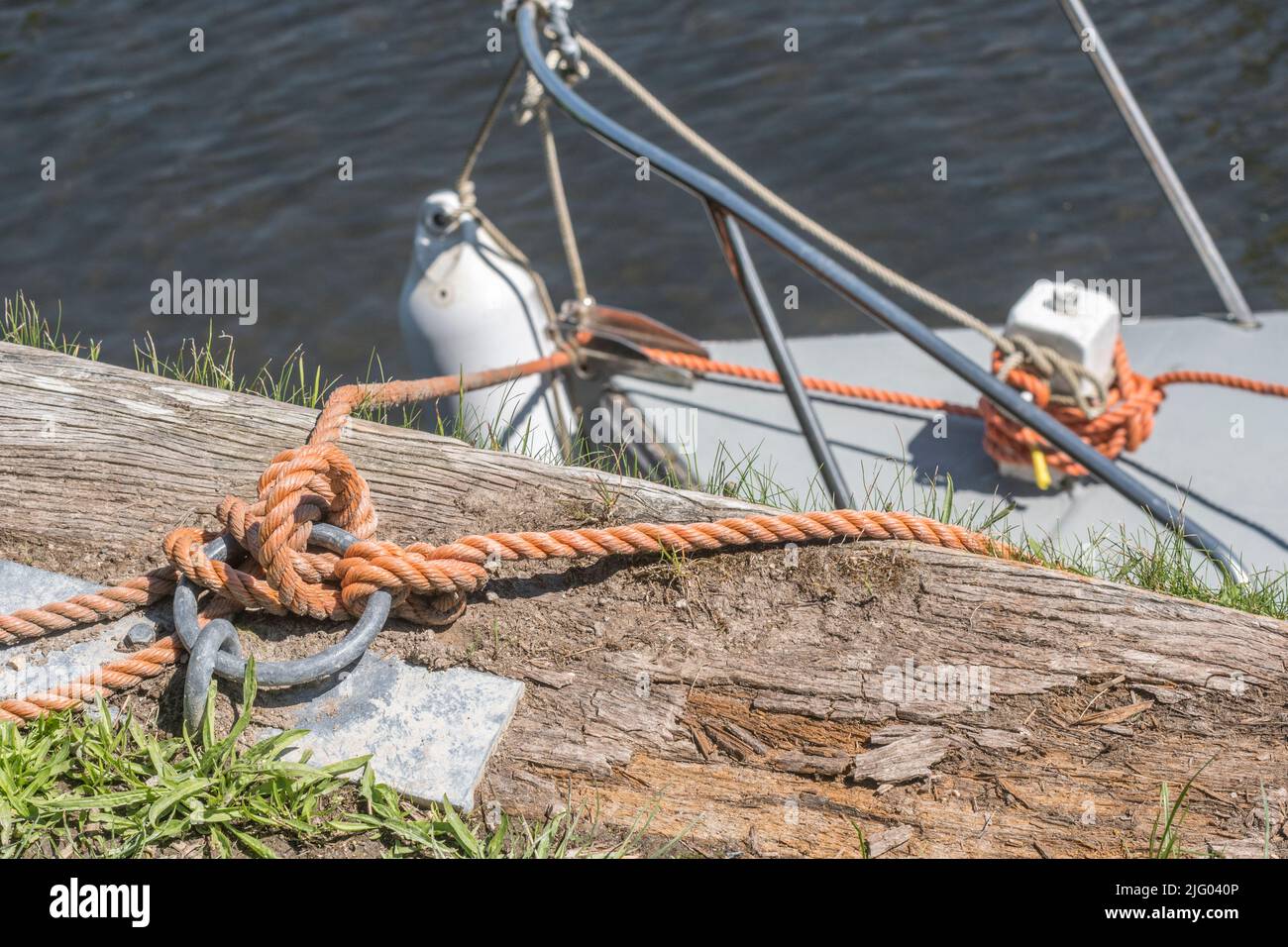Sunny quayside with boat mooring rope attached to metal mooring ring. For UK sailing and boating activities, something secured, tethered, tied up. Stock Photo
