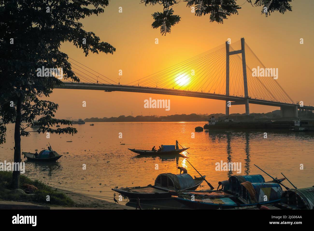 Kolkata, 20,March,2013; Panoramic view of Vidyasagar Setu, bridge with   setting Sun reflection and local boats in river Hooghly Kolkata, West Bengal. Stock Photo