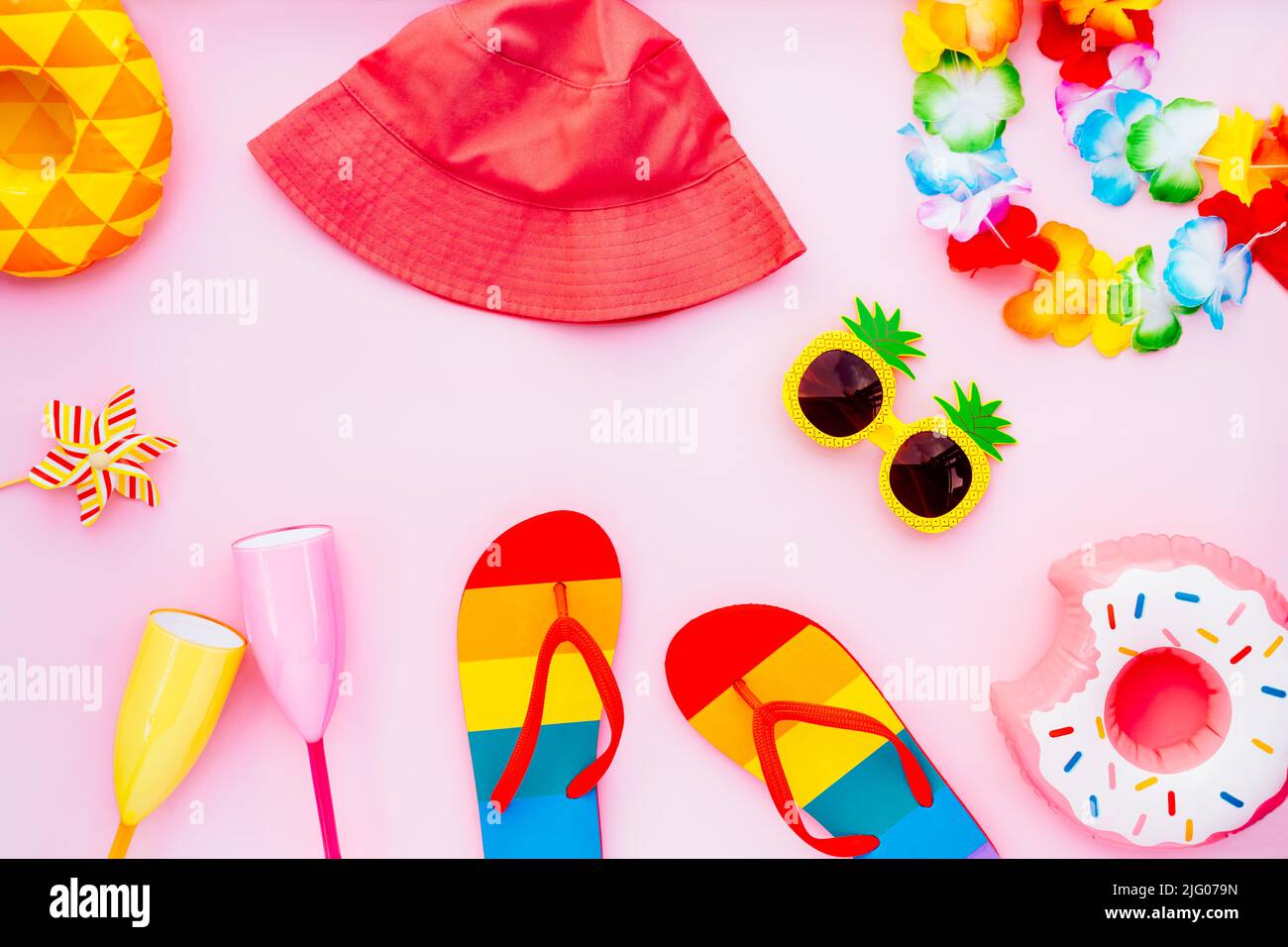 Flat lay of summer vibes concept with colorful pool party items, funny sunglasses, cocktail glasses. inflatable drink holders, flip flops, bucket hat, Stock Photo