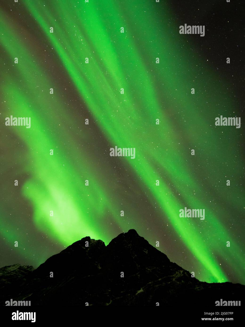 A breathtaking view of green Northern lights over mountain silhouettes ...