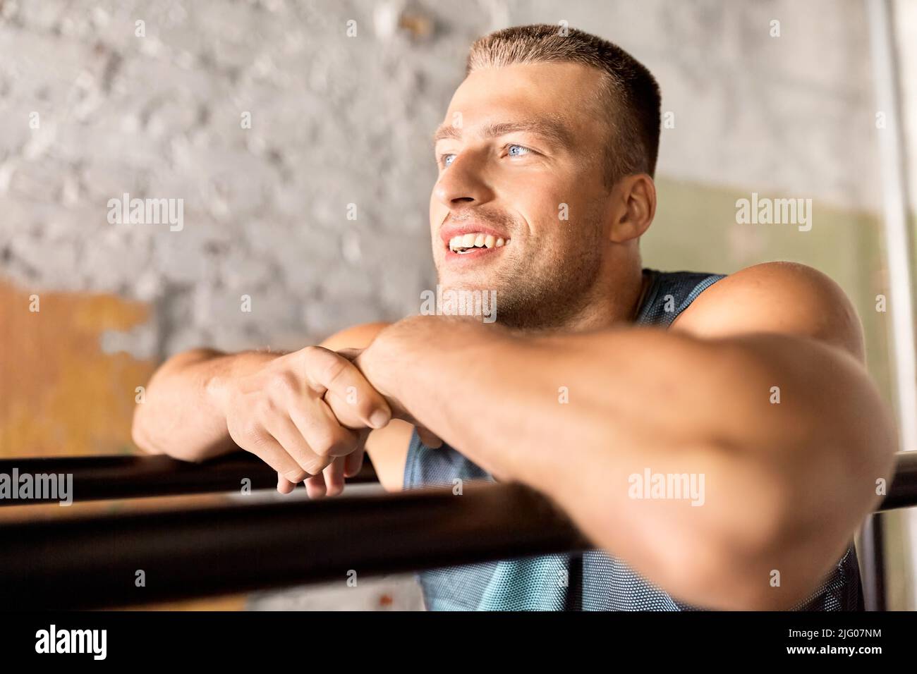 smiling young man at parallel bars in gym Stock Photo - Alamy