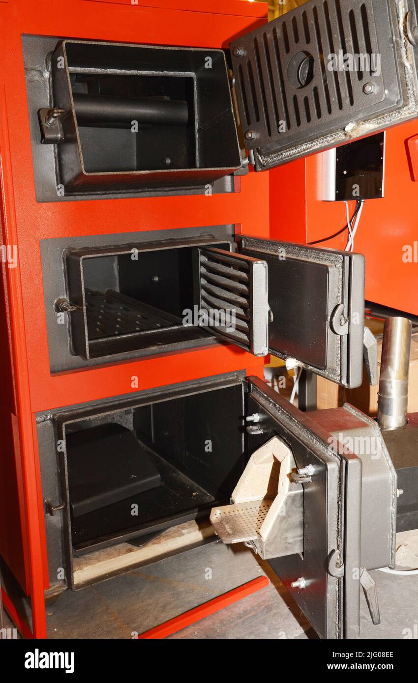 A closeup of an open solid fuel burning stove, boiler, furnace. A red multi fuel boiler with