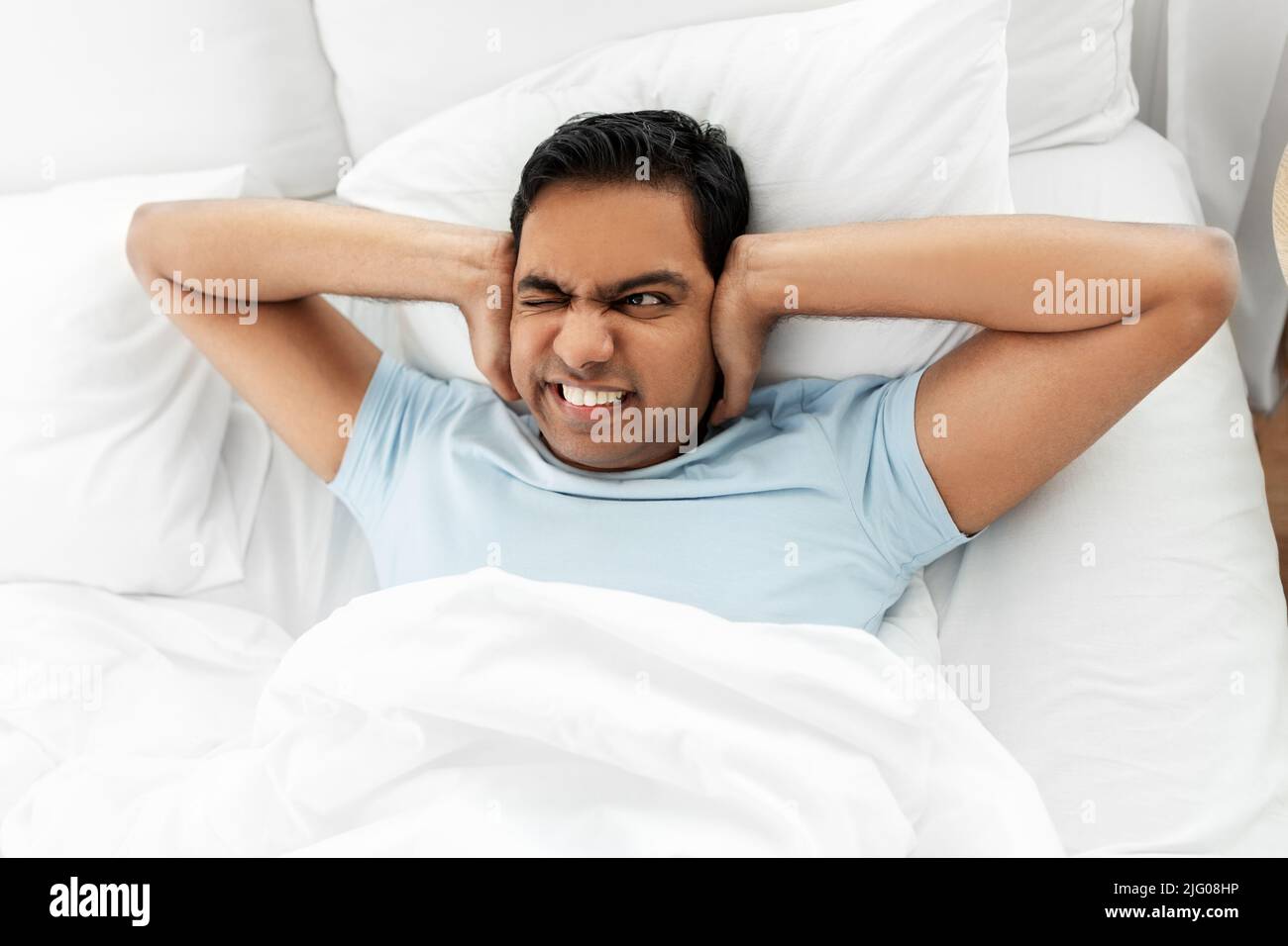 annoyed indian man lying in bed and closing ears Stock Photo Alamy