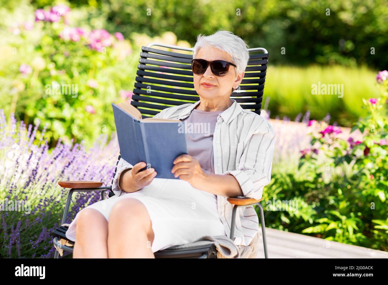 happy senior woman reading book at summer garden Stock Photo - Alamy
