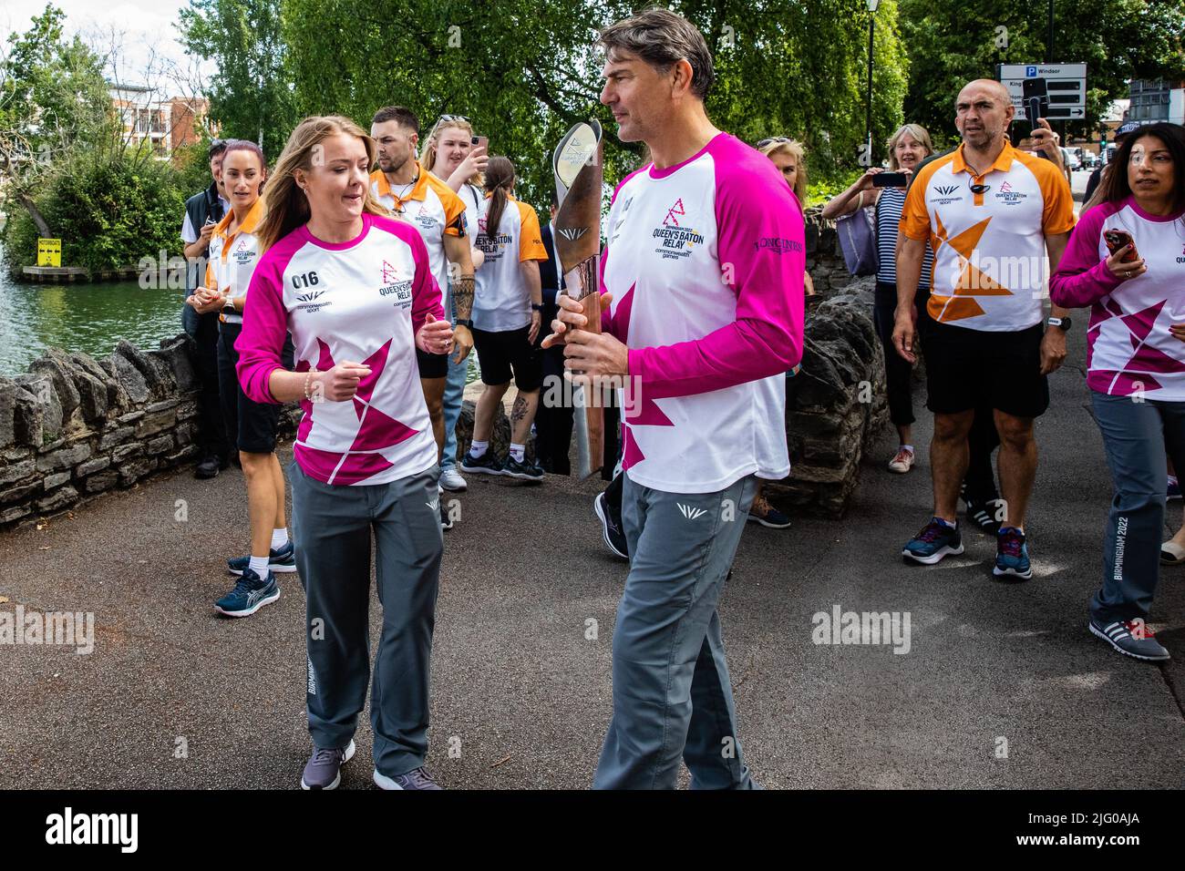 Windsor and Eton, UK. 6th July, 2022. Batonbearers Jemma Wood and Ray Stevens exchange the Queen's Baton alongside the River Thames during the Queen's Baton Relay. The Queen's Baton is currently on a 25-day tour of the English regions en route to the Commonwealth Games. Credit: Mark Kerrison/Alamy Live News Stock Photo
